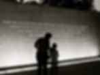 A mother and child stand in front of an MLK monument and quotation that says, "If we are to have peace on earth, our loyalties must become ecumenical rather than sectional. Our loyalties must transcend our race, our tribe, our class, and our nation; and this means we must develop a world perspective."